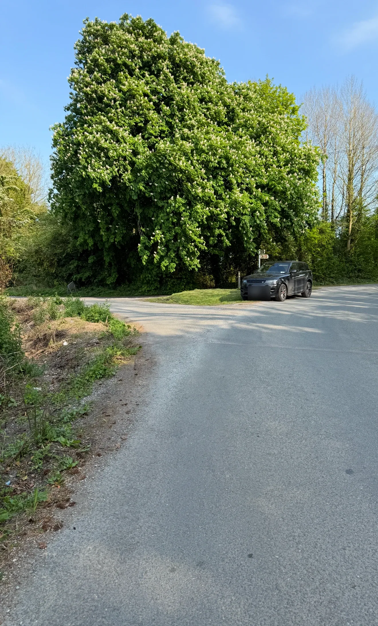 An open channel dug along the roadside beside the bend, with loose material on the road.