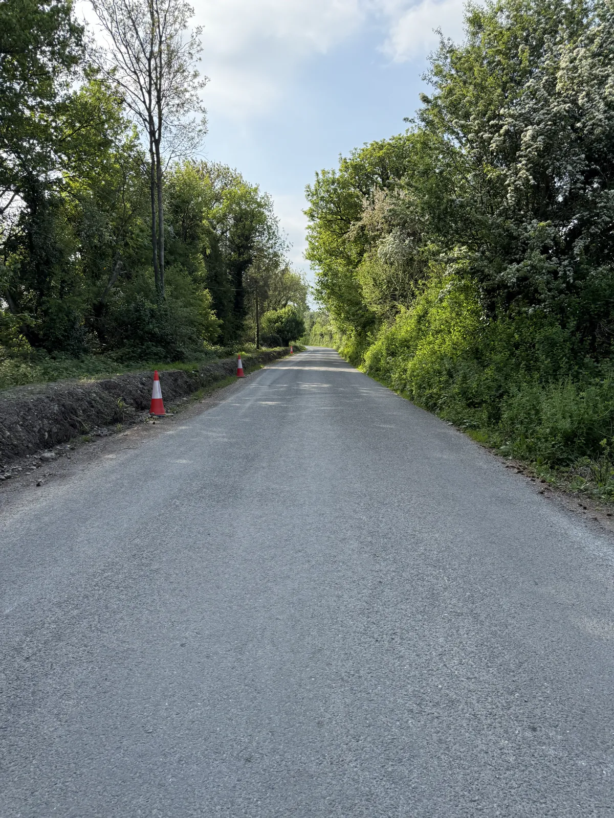 Left-hand roadside excavation/open line visible, 1 May 2025 family photograph; drainage function unproven.