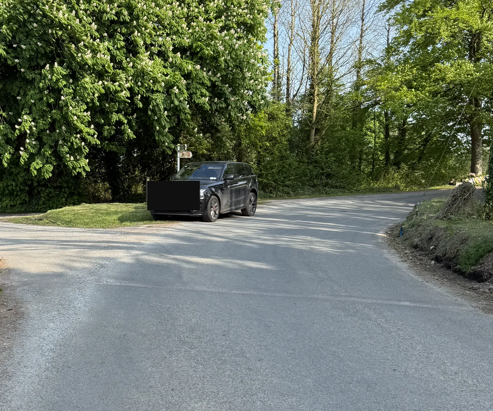 Context view of the right-side cut bank at the turn; numberplate obscured by an opaque plate-only mask.